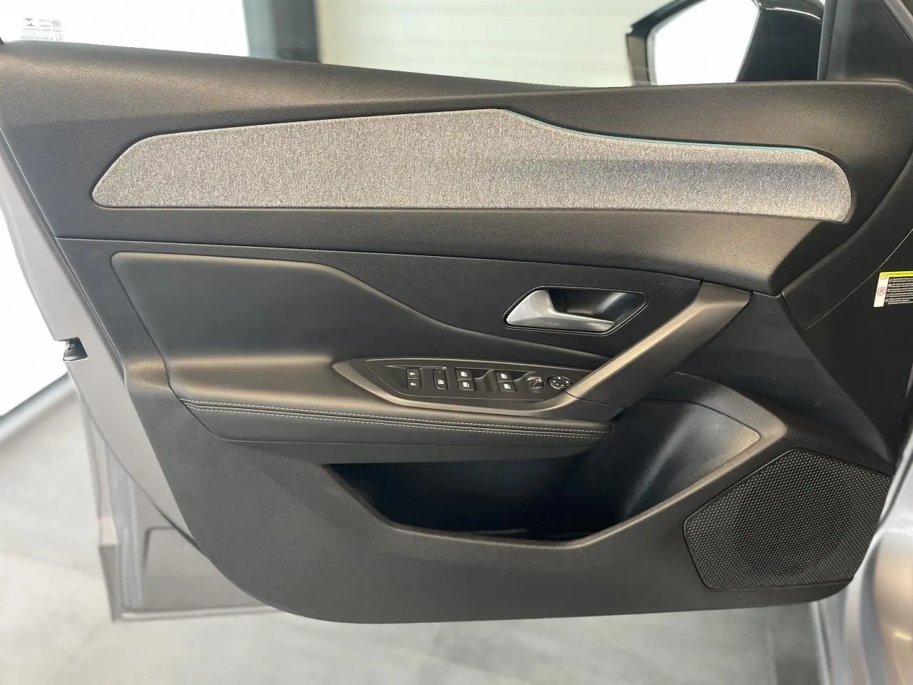 Intérieur côté gauche de la porte avant gris Artense du Peugeot 308 2022 avec commandes de vitres et poignée métallique.