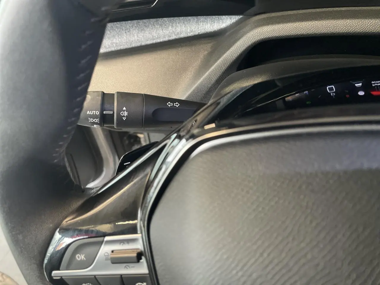 Détail du volant en cuir noir avec commandes intégrées et manette de clignotants sur Peugeot 308 gris Artense.