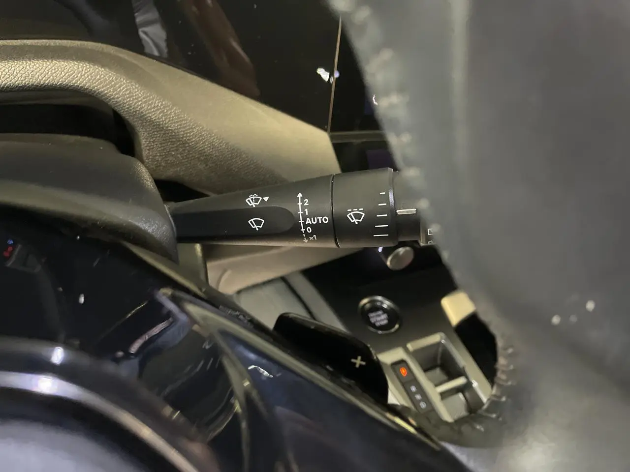 Gros plan sur la commande d'essuie-glace à gauche du volant en cuir de la Peugeot 308 gris Artense 2022.