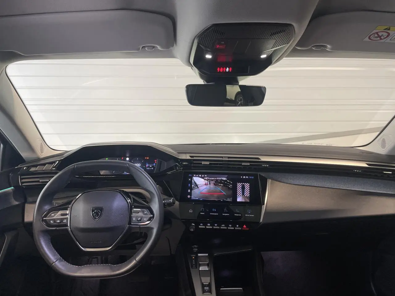 Vue intérieure avant du poste de conduite de la Peugeot 308 gris Artense avec écran tactile affichant la caméra de recul.