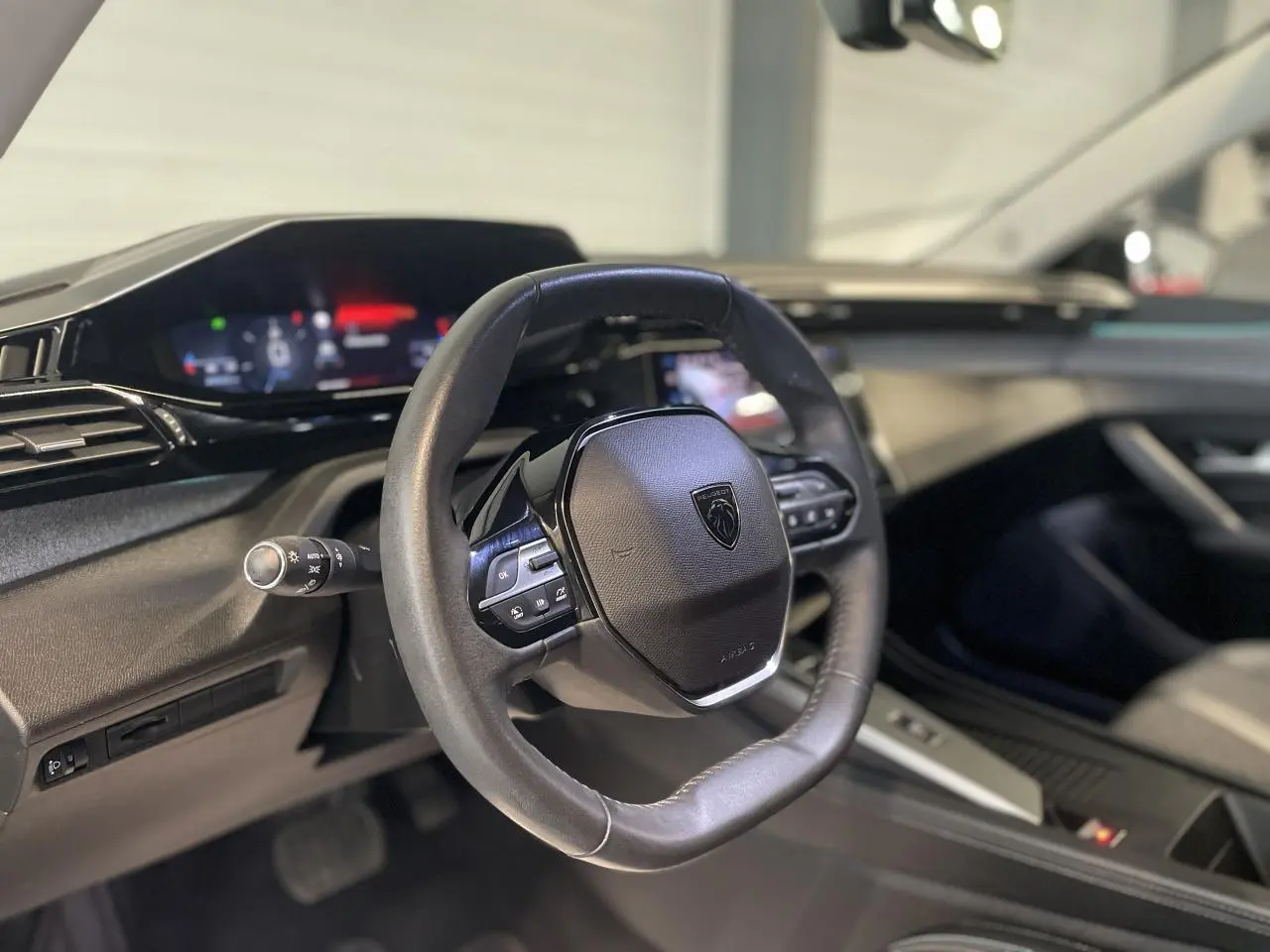 Vue rapprochée du volant cuir noir et du tableau de bord numérique de la Peugeot 308 gris Artense 2022.