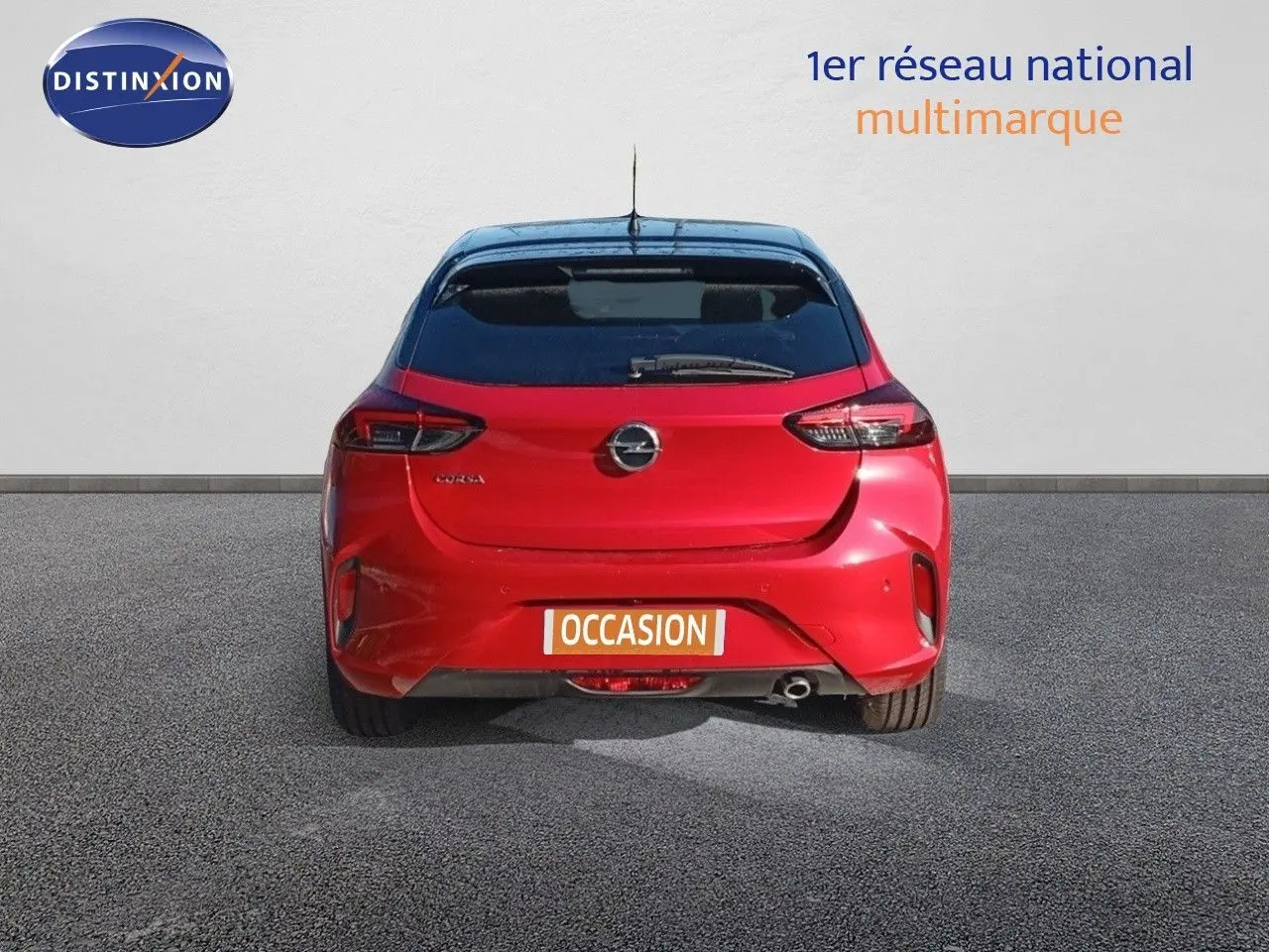 Vue arrière d'une Opel Corsa 2023 rouge Kardio métal avec toit noir, garée sur un sol gris.