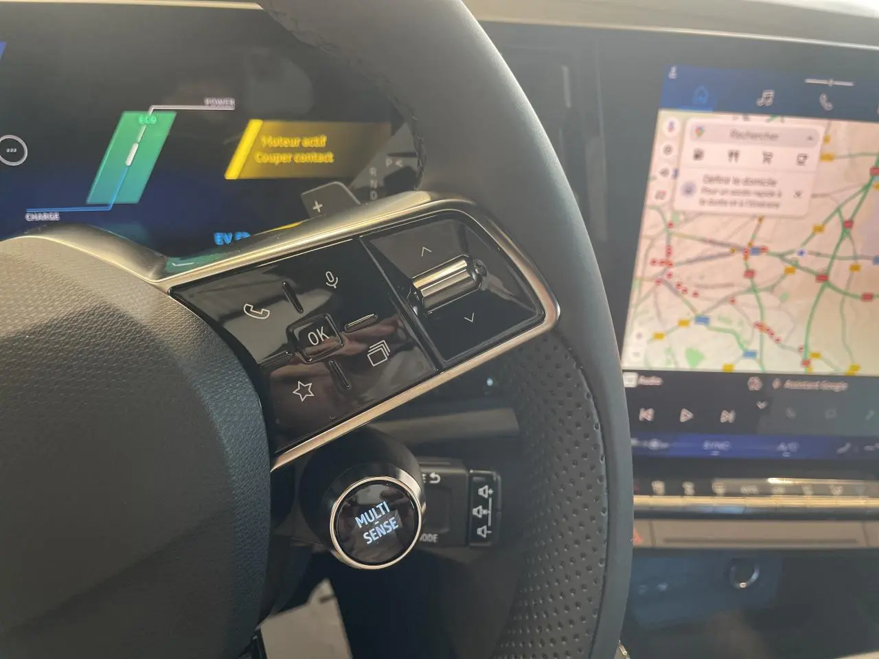 Gros plan sur le volant noir perforé du Renault Rafale 2025 avec bouton Multi-Sense et écran tactile de navigation visible.