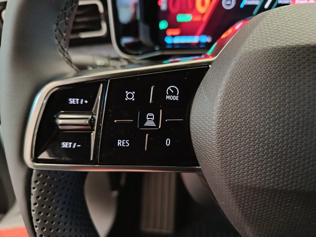 Gros plan sur les commandes de régulateur de vitesse au volant de la Renault R5 Techno 150 ch blanc, intérieur moderne.