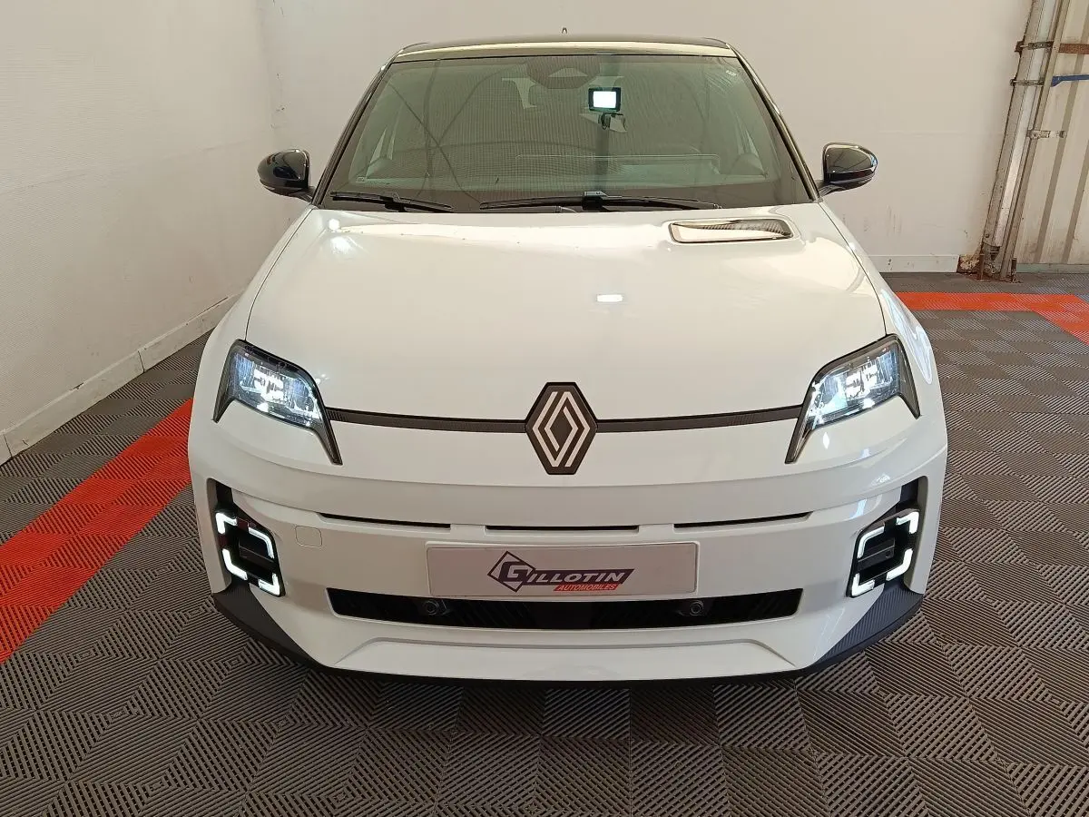 Vue avant d'une Renault R5 Techno électrique blanche avec phares LED allumés et détails noirs contrastants.