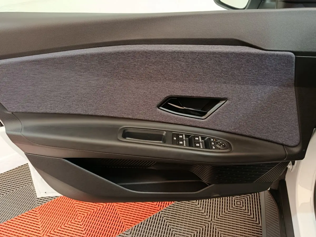 Vue rapprochée de la porte avant gauche blanche de la Renault R5 Techno 2025 avec garniture tissu gris et commandes électriques.