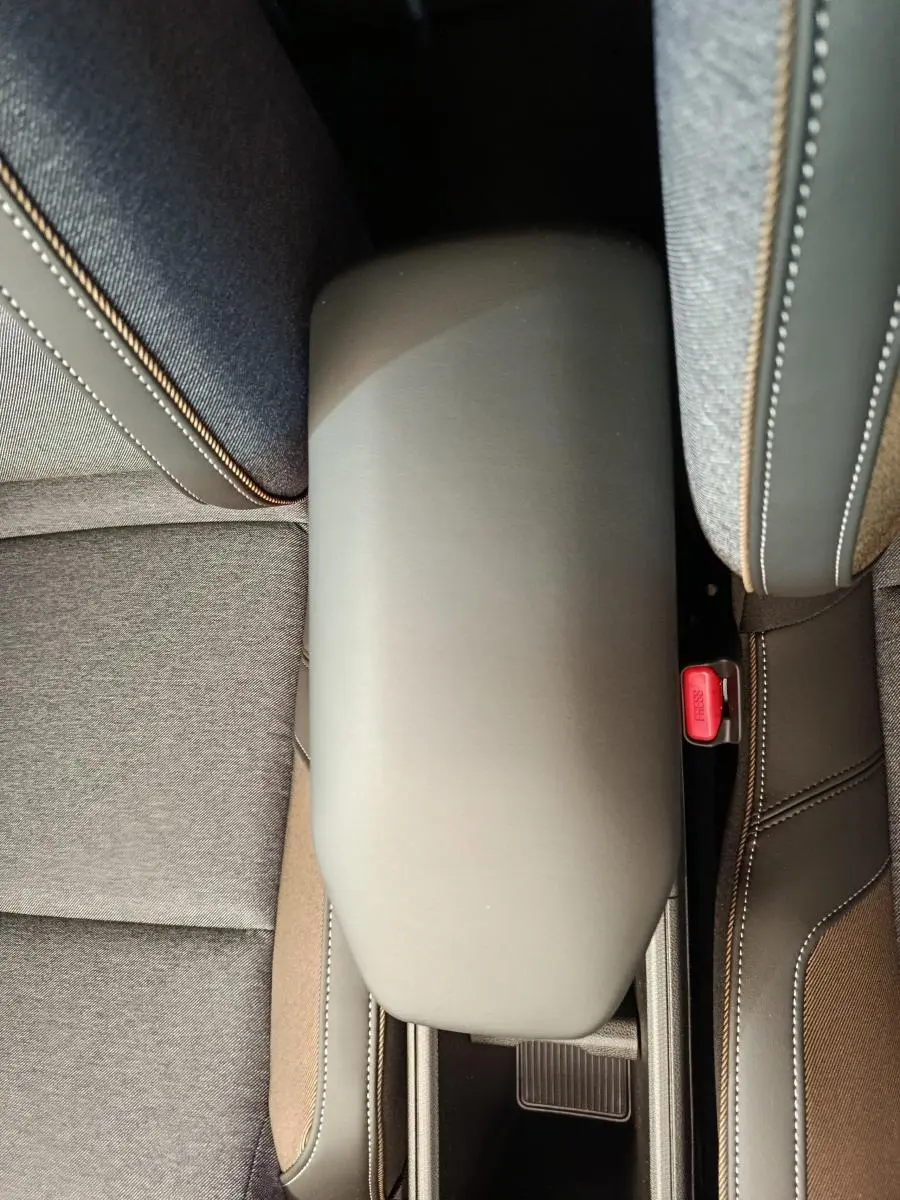 Vue plongeante sur l'accoudoir central gris et les sièges tissu gris du Renault R5 Techno 150 ch 2025.