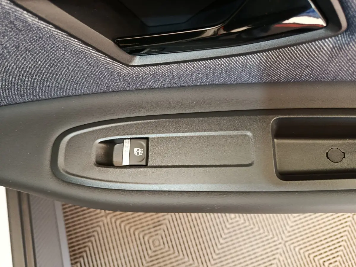 Gros plan sur le bouton de commande de la fenêtre électrique côté conducteur de la Renault R5 Techno 150 ch blanche 2025.