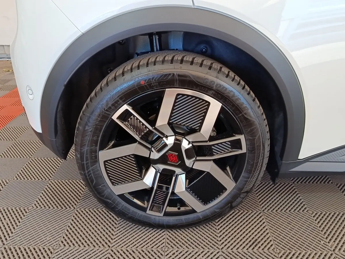 Gros plan sur la roue avant droite blanche d'une Renault R5 Techno 150 ch avec jante noire et argentée au design géométrique.