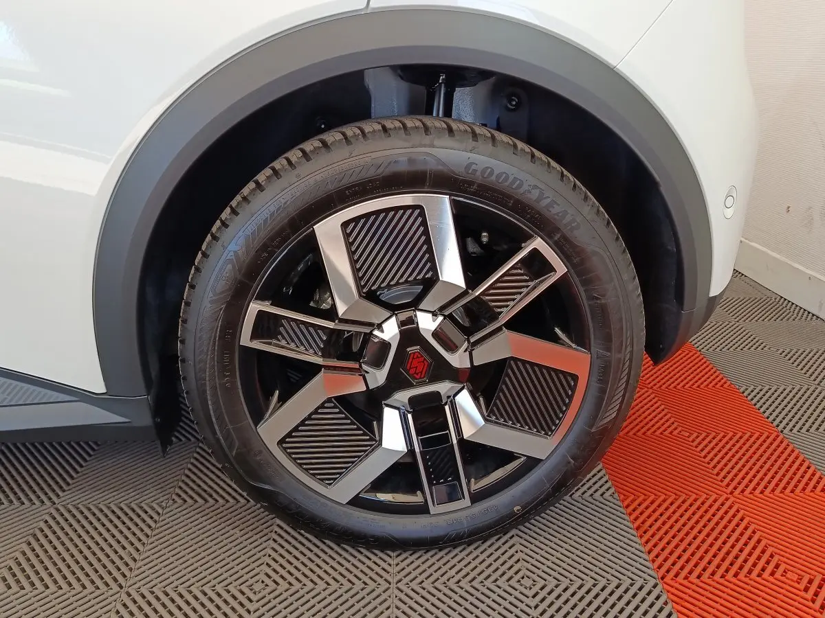 Gros plan sur la roue avant droite de la Renault R5 Techno blanche, avec jante noire et argentée au design géométrique.