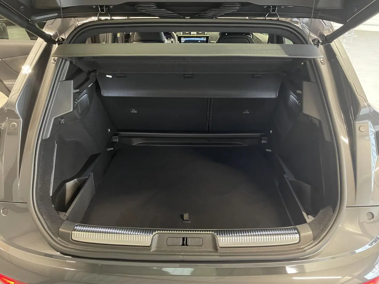 Coffre ouvert vu de l'arrière du DS7 Crossback gris titanium avec seuil de coffre chromé et intérieur noir.