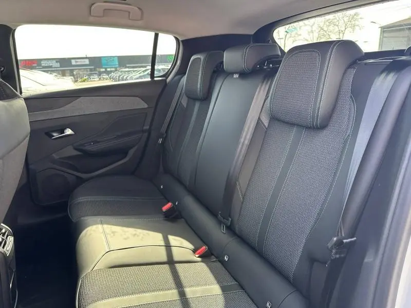 Vue latérale intérieure montrant la banquette arrière en tissu gris et noir de la Peugeot 308 2025.