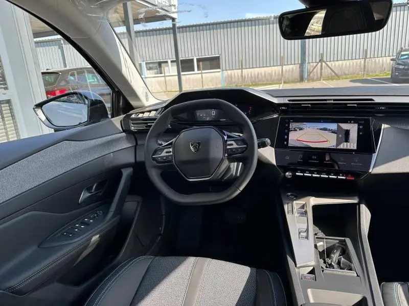 Vue intérieure avant de la Peugeot 308 2025 bleu, volant multifonction et écran tactile affichant la caméra de recul.