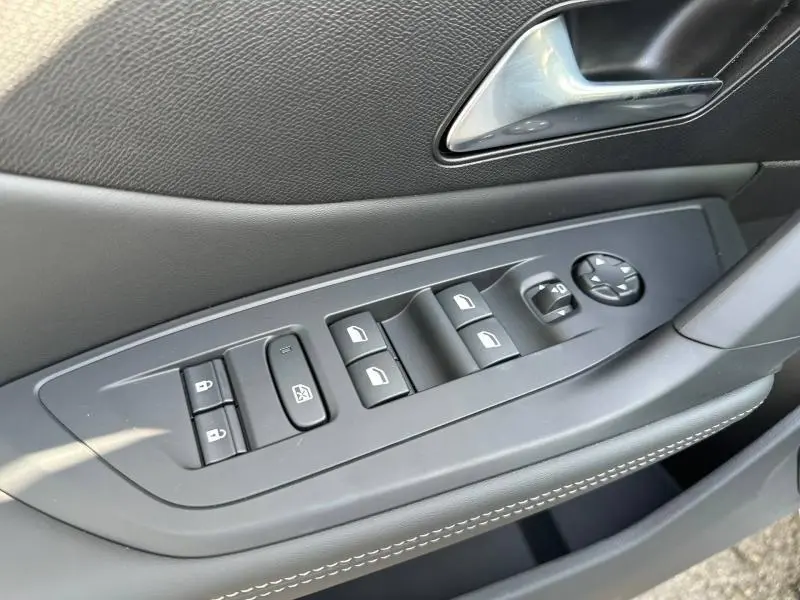 Détail de la porte avant gauche de la Peugeot 308 2025 bleu, avec commandes des vitres et rétroviseurs électriques.