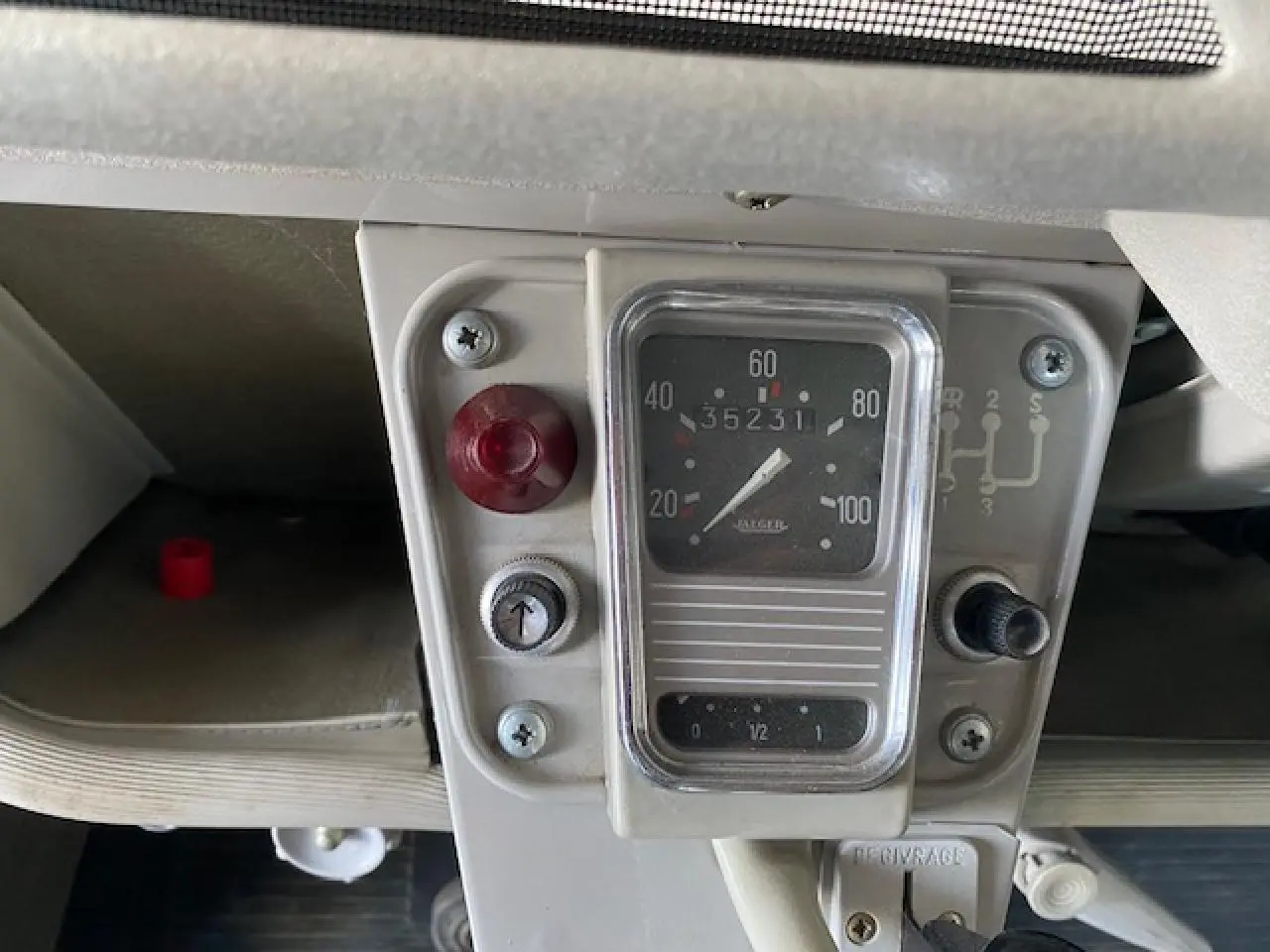 Gros plan sur le compteur de vitesse beige clair d'une Citroën 2 CV 1968 refaite à neuf, avec indicateur manuel de vitesses.