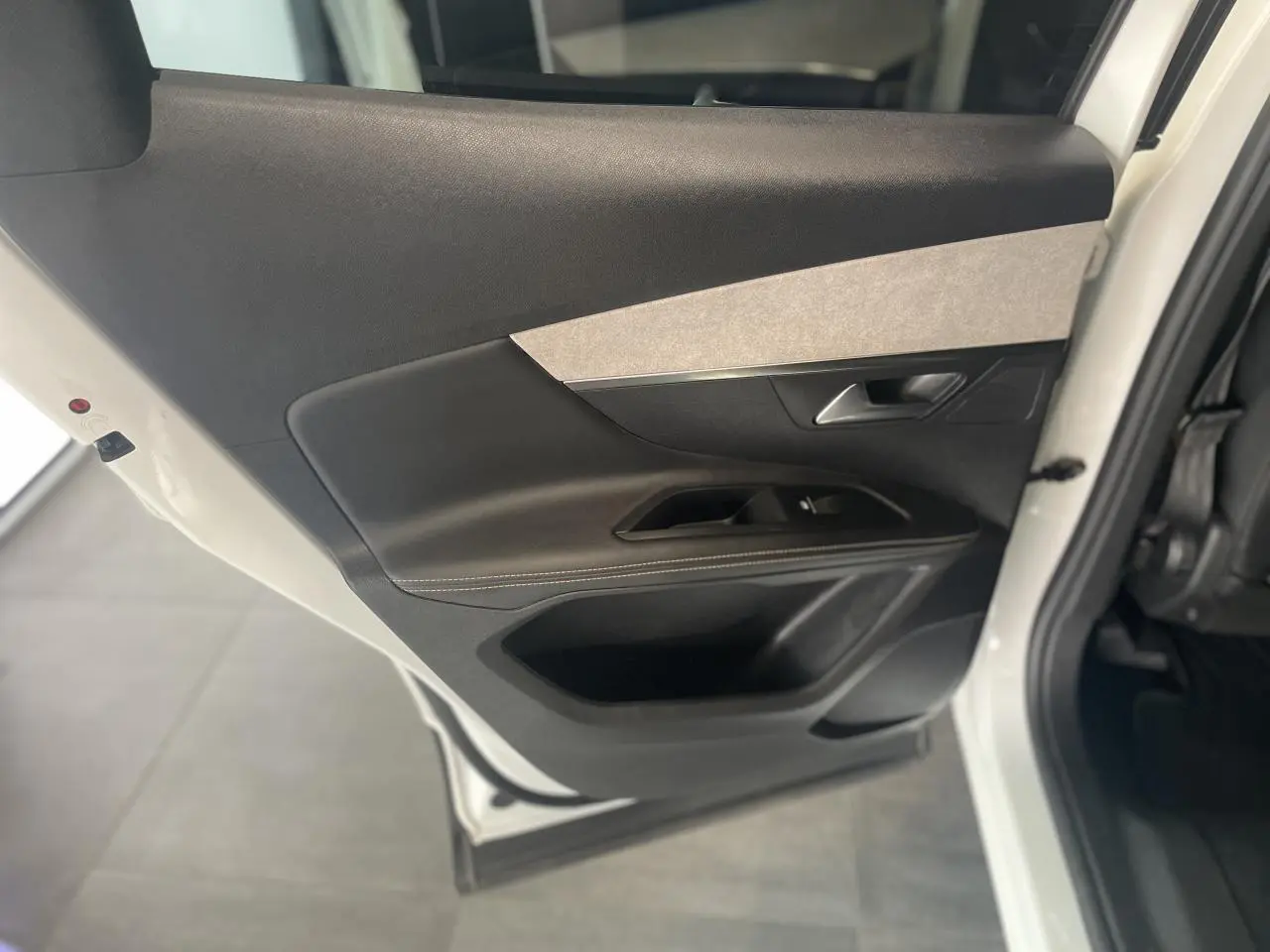 Porte arrière gauche ouverte du Peugeot 3008 blanc nacré, avec garniture intérieure noire et insert gris clair.