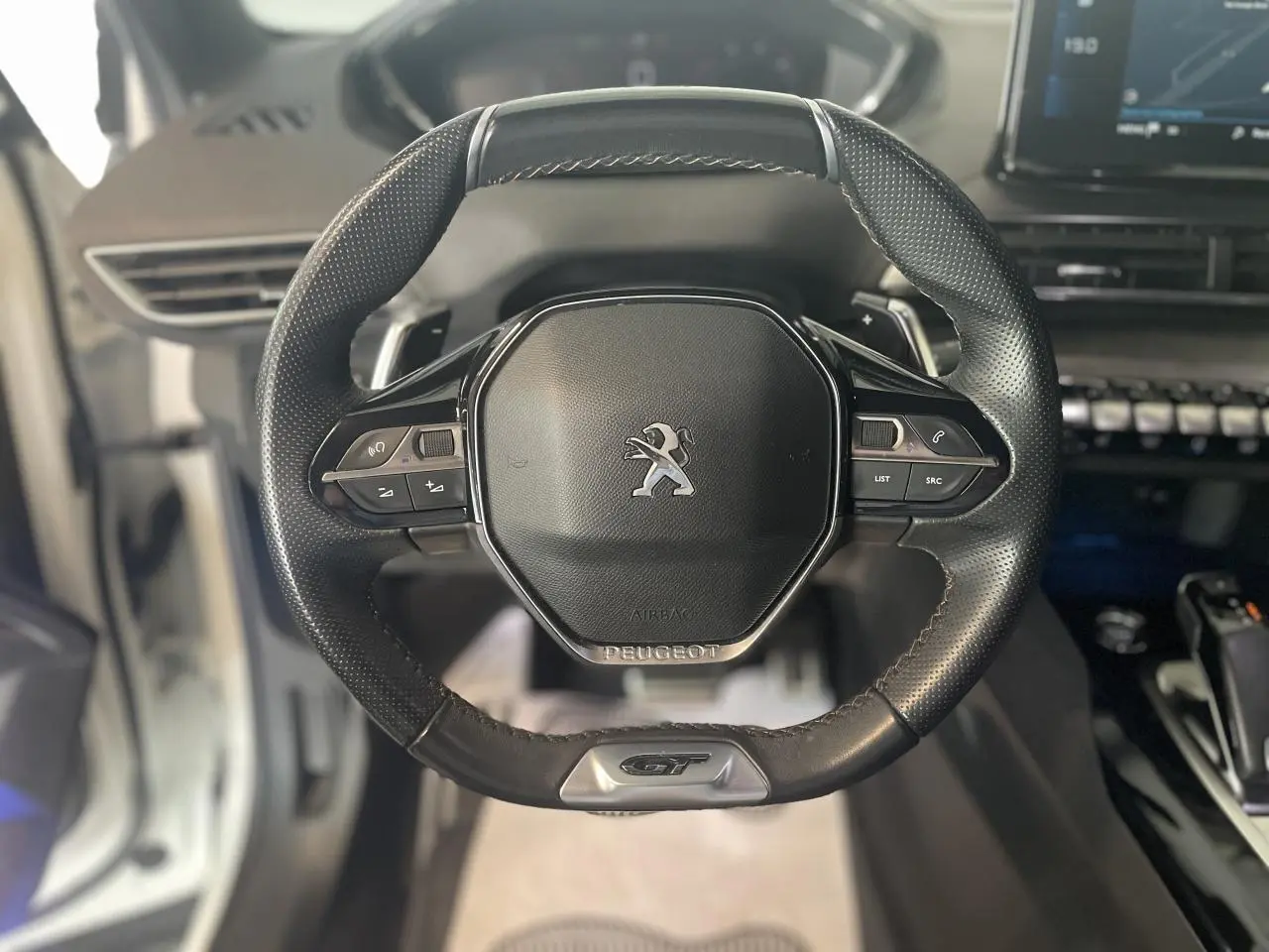 Volant cuir perforé Peugeot 3008 GT vu de face avec badge GT et commandes intégrées sur un intérieur noir Mistral.