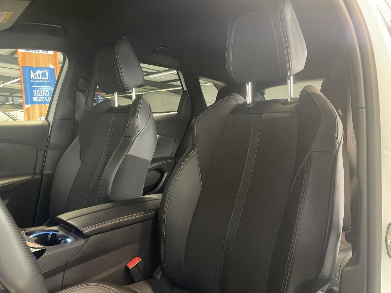 Gros plan sur les sièges avant noirs du Peugeot 3008 GT 2022, avec accoudoir central et coutures contrastées.