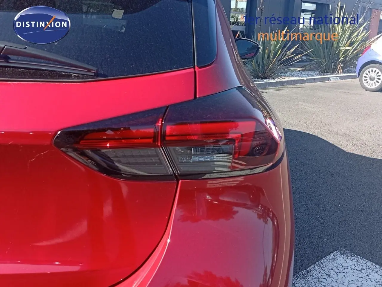 Gros plan sur le feu arrière droit d'une Opel Corsa 2023 rouge Kardio métal avec toit noir, vue arrière côté droit.