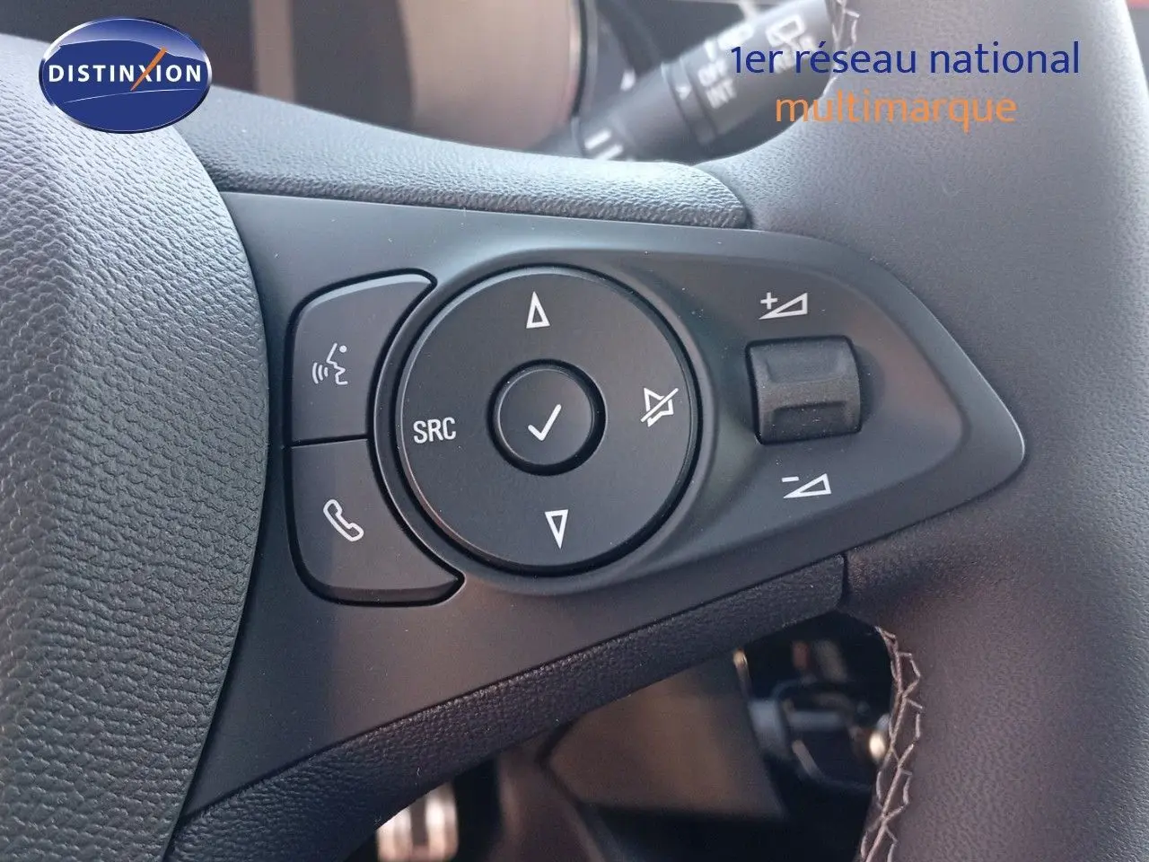 Gros plan sur les commandes audio au volant d'une Opel Corsa 2023, finition rouge Kardio métal avec toit noir.