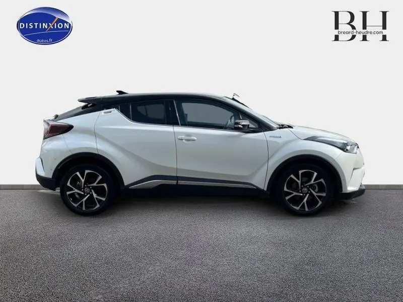 Profil côté gauche du Toyota C-HR 122h Collection 2WD blanc nacré bi-ton avec jantes alu et toit noir.