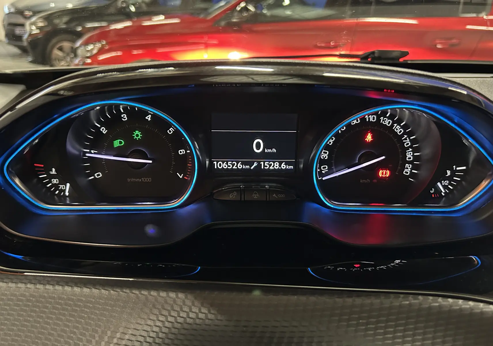 Vue rapprochée du tableau de bord numérique bleu et noir du Peugeot 2008 blanc, affichant 106526 km et 0 km/h.