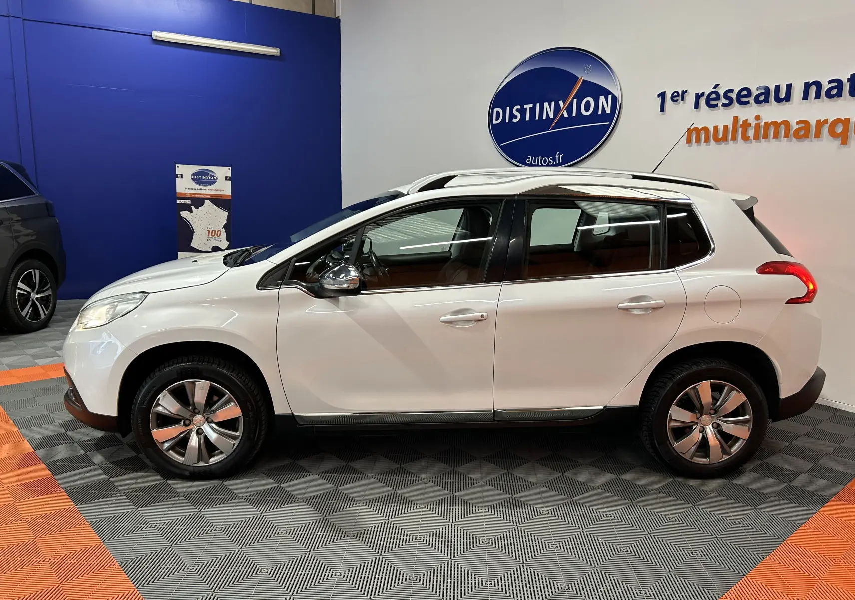 Vue de profil côté gauche d'un Peugeot 2008 blanc 5 portes en intérieur avec jantes alliage et rétroviseurs chromés.