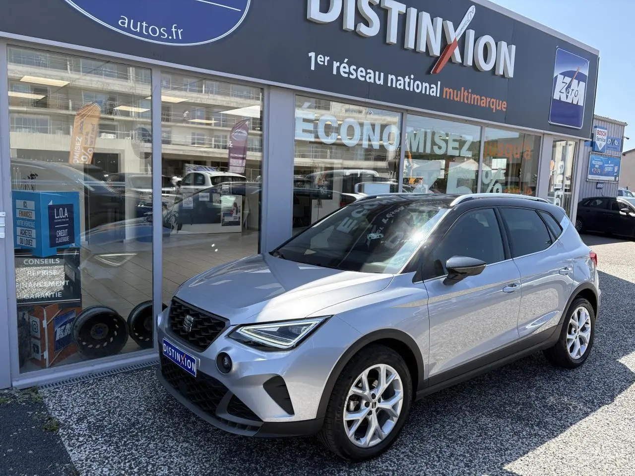 SEAT Arona 2024 gris GRS en 3/4 avant droit, avec jantes alliage 16 pouces et calandre noire distinctive.