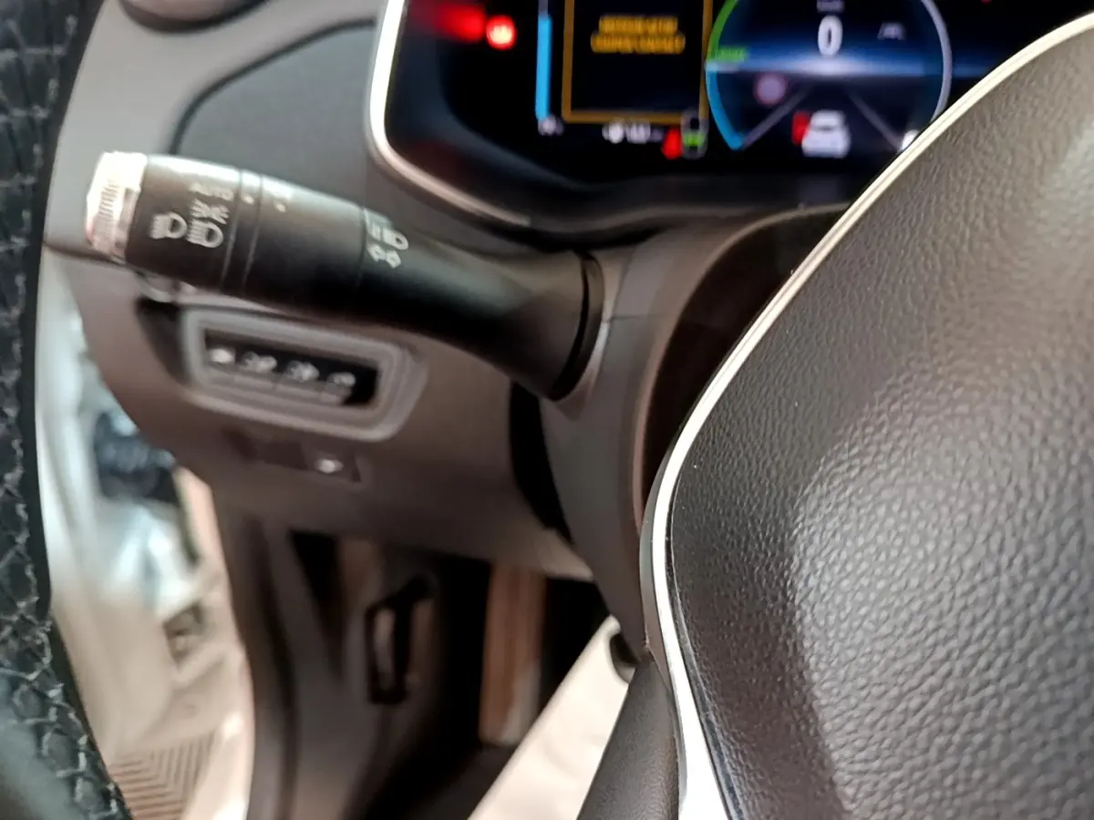 Gros plan sur le volant cuir noir et la commande des phares de la Renault ZOE Business R110 2021.