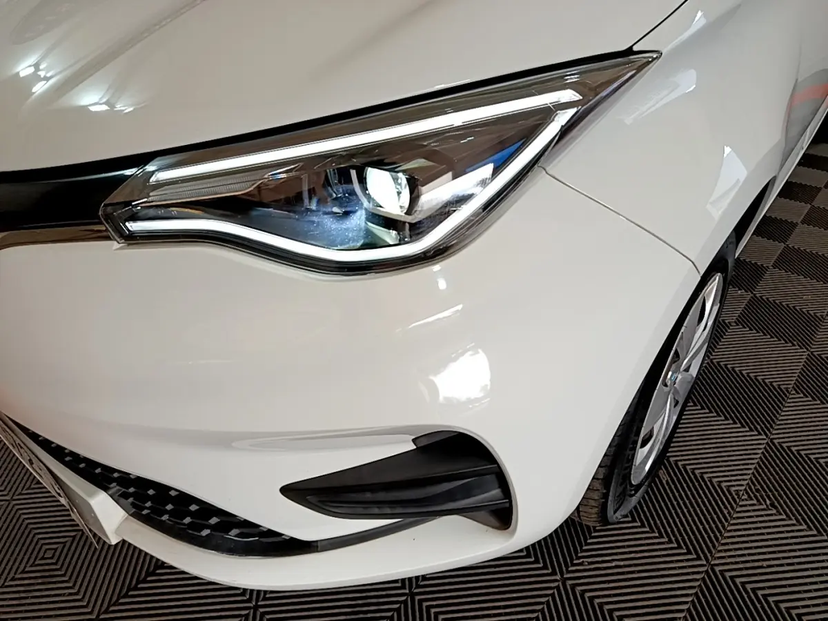Gros plan sur le phare avant droit blanc de la Renault ZOE Business R110, avec détails du pare-chocs et roue.