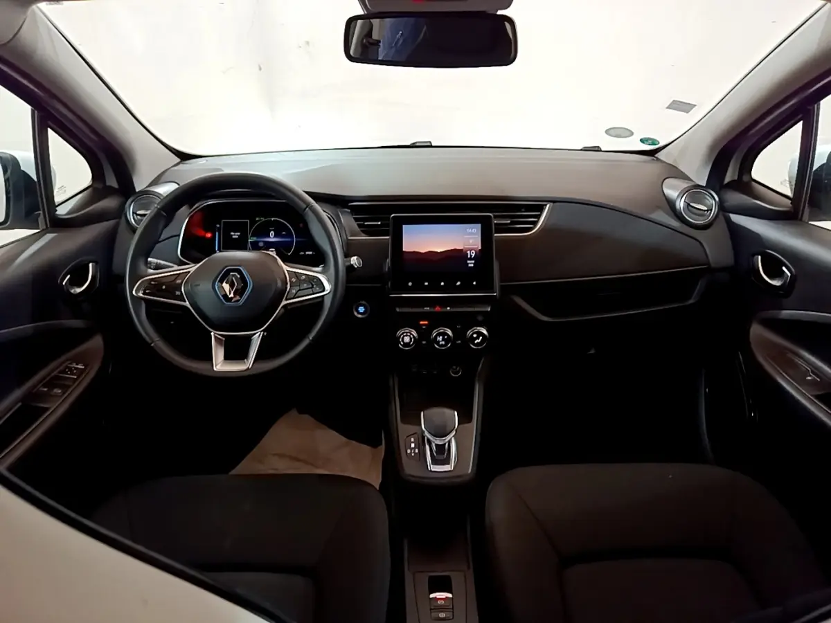 Vue intérieure frontale du tableau de bord noir de la Renault ZOE Business R110 avec écran tactile central et volant multifonctions.