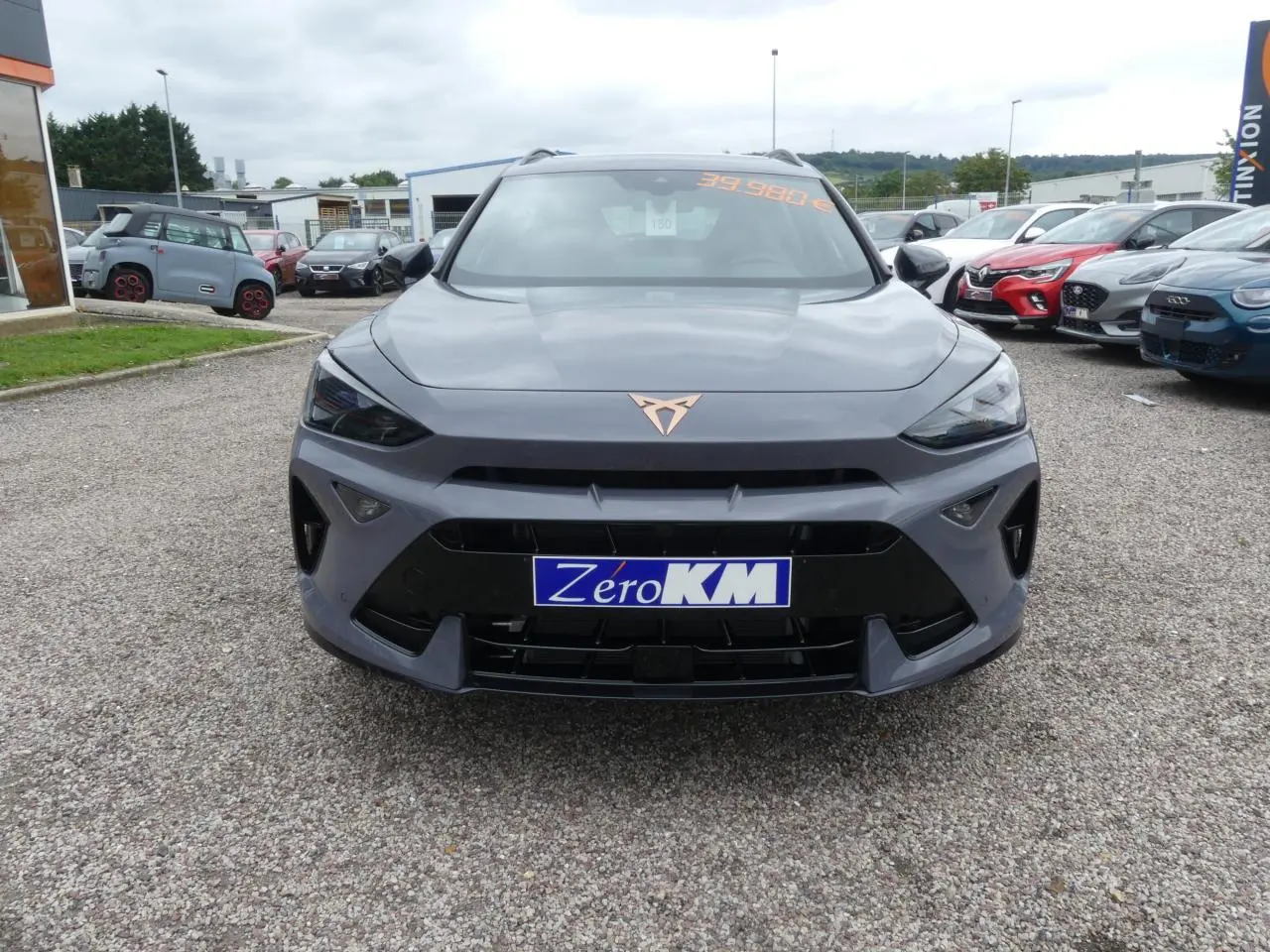 Vue frontale d'un CUPRA Formentor gris Graphène avec logo cuivre et calandre noire, stationné en extérieur.