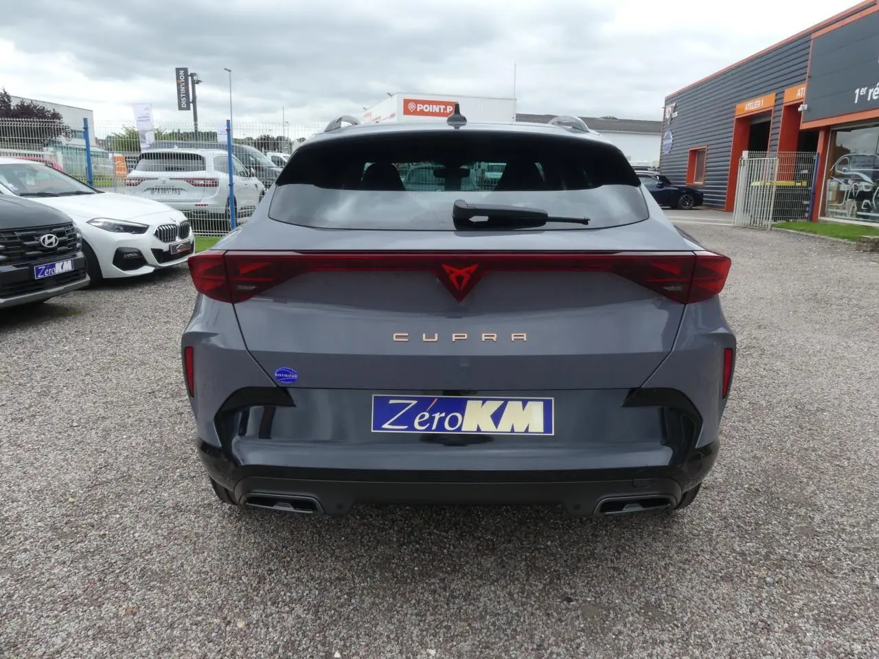 Vue arrière d'une CUPRA Formentor gris Graphène avec logo rouge et double sortie d'échappement noire.