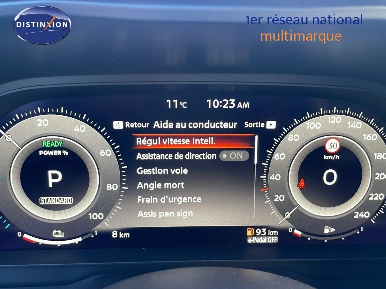 Tableau de bord numérique du Nissan Qashqai blanc nacré, affichant les aides à la conduite et la vitesse à 0 km/h.