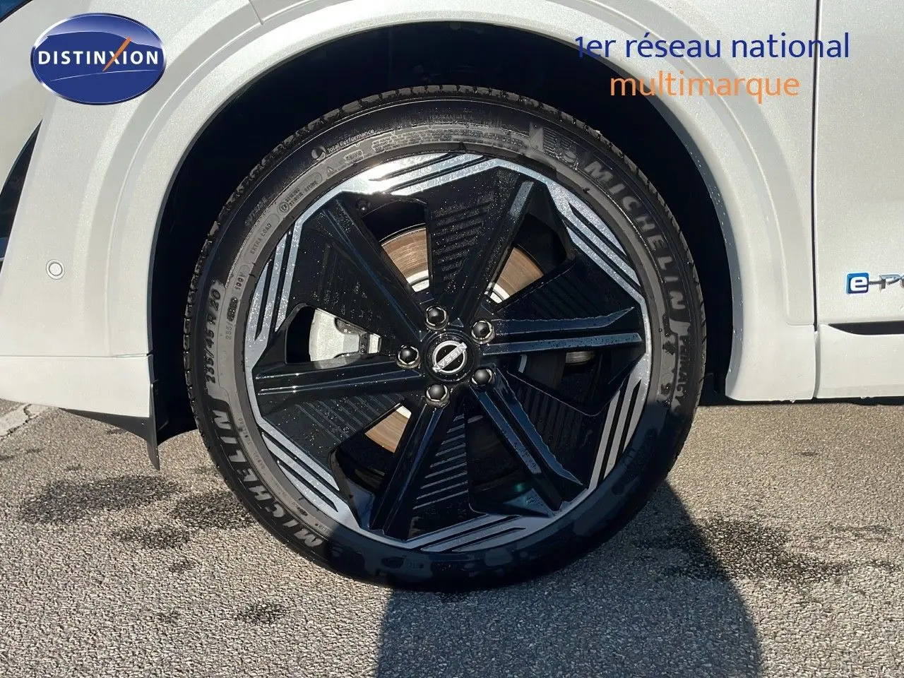 Gros plan sur la roue avant droite du Nissan Qashqai blanc nacré avec jante noire et détails gris métallisé.