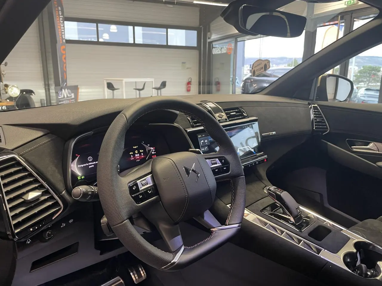 Vue intérieure côté conducteur du DS7 Crossback gris titanium, mettant en valeur le volant cuir perforé et l'écran tactile central.