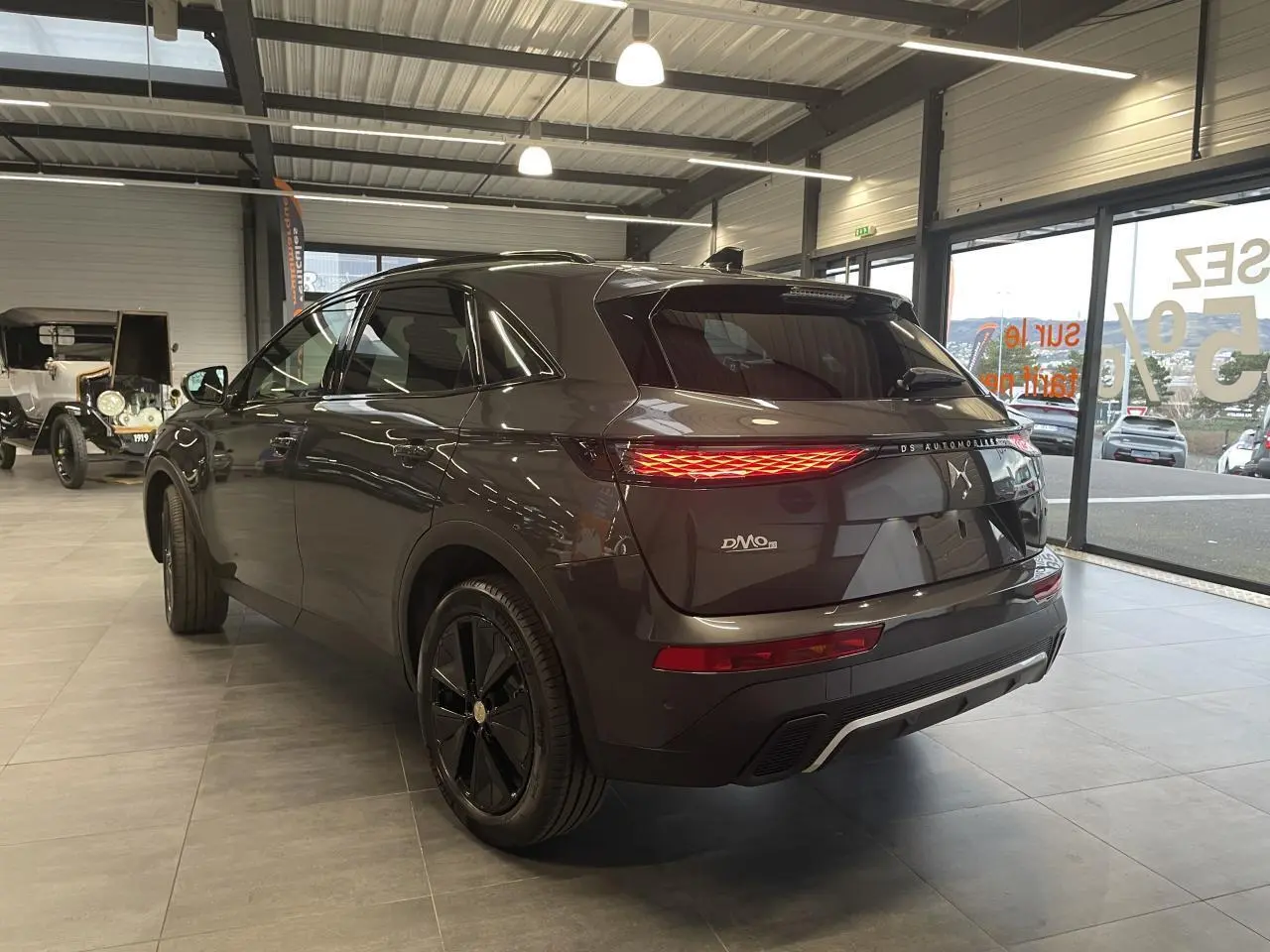 Vue 3/4 arrière droit du DS7 Crossback gris titanium avec feux arrière LED et jantes noires en showroom.