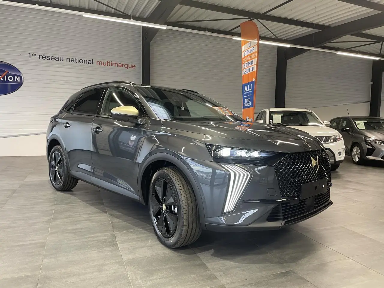 DS7 Crossback gris titanium en 3/4 avant droit avec calandre noire et feux LED distinctifs en showroom.