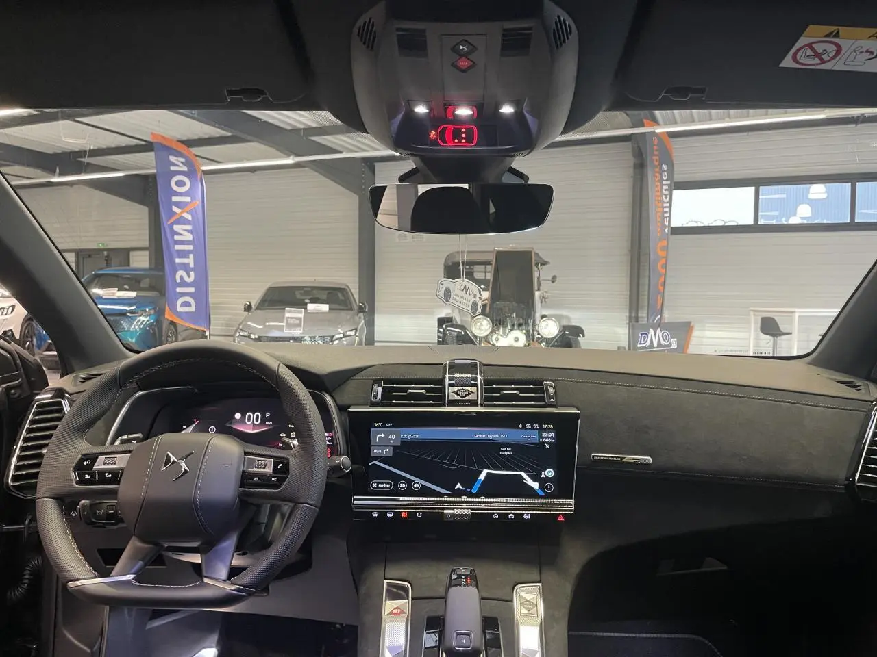 Vue intérieure avant du DS7 Crossback gris titanium, mettant en valeur le volant cuir perforé et l'écran tactile central HD.