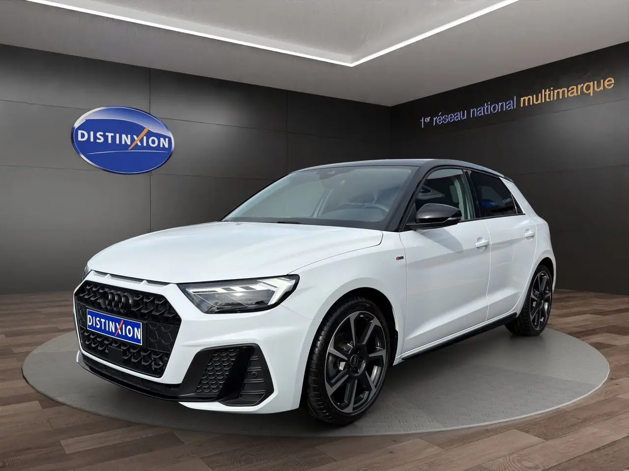 Audi A1 Sportback blanc avec toit noir, vue 3/4 avant droit, jantes 18 pouces noires et calandre hexagonale.
