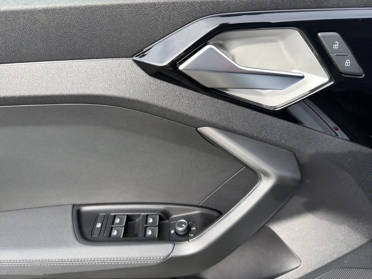 Détail de la porte intérieure côté gauche de l'Audi A1 Sportback 2025 avec commandes de vitres et poignée argentée.