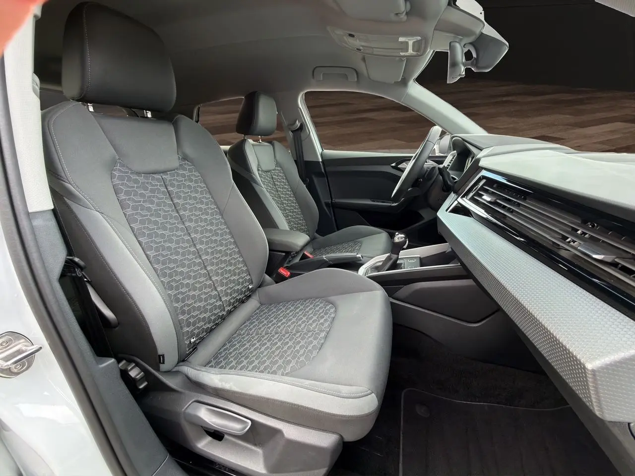 Vue intérieure côté conducteur de l'Audi A1 Sportback 2025 avec sièges tissu gris et tableau de bord clair.