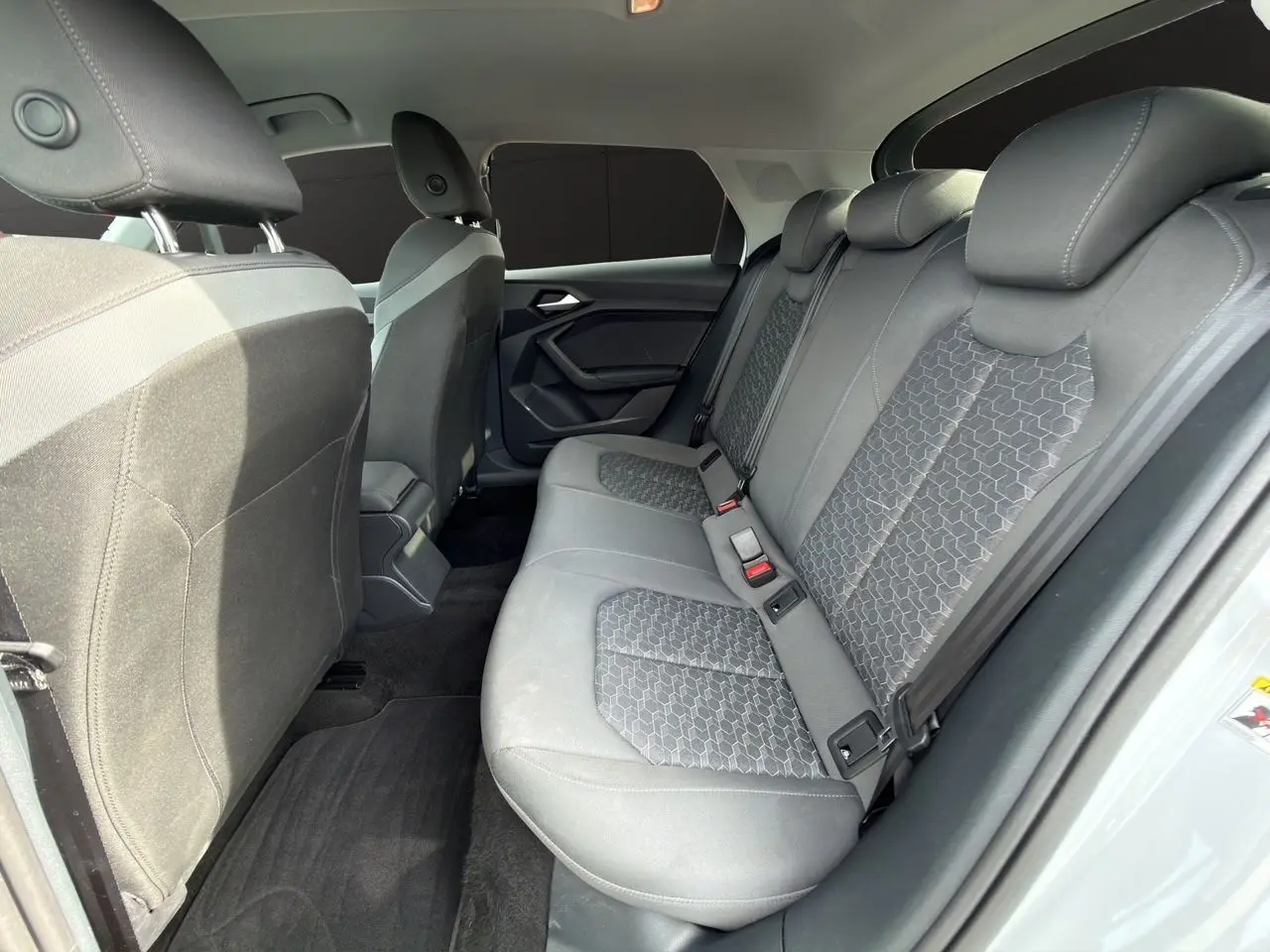 Vue intérieure arrière côté droit de l'Audi A1 Sportback 2025 avec sièges tissu noir à motifs hexagonaux.