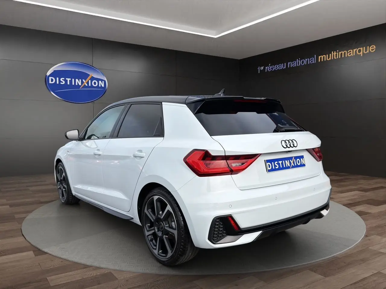 Audi A1 Sportback blanc avec toit noir, vue 3/4 arrière droit, jantes 18 pouces et feux LED distinctifs.