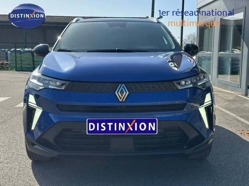 Vue frontale d'un Renault Captur 2025 bleu Iron avec calandre noire et éclairage LED distinctif, plaque Distinxion visible.