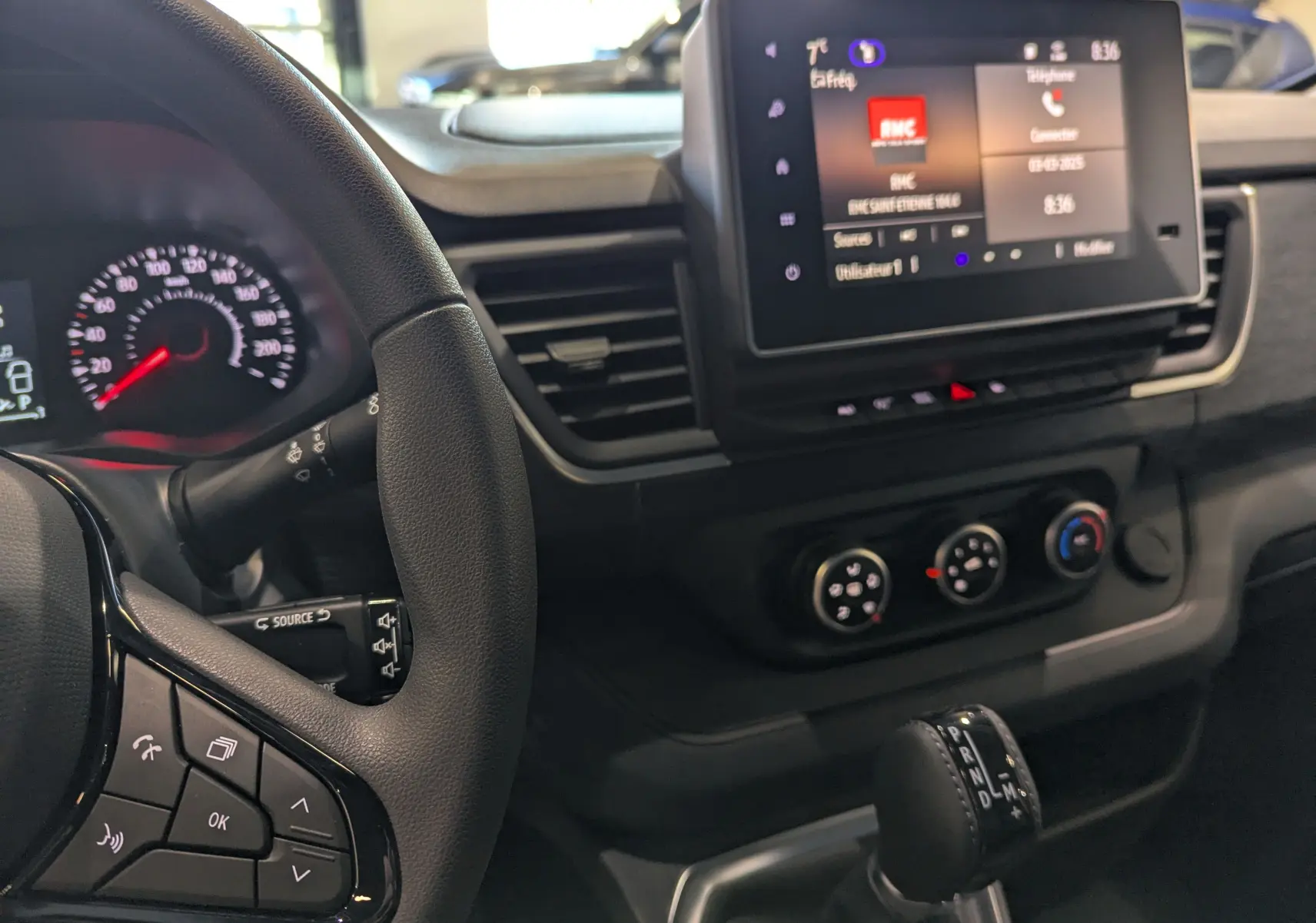 Vue intérieure du tableau de bord du Renault Trafic Fourgon 2025, avec volant, écran tactile et levier de boîte automatique.
