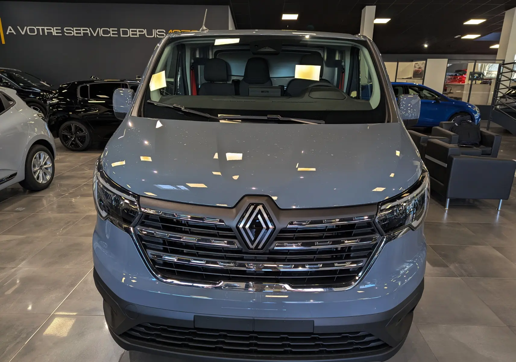Vue de face du Renault Trafic Fourgon L2H1 2025 en gris urbain, avec calandre chromée et logo Renault bien visible.