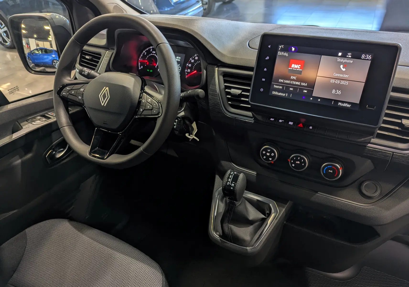 Vue intérieure côté conducteur du Renault Trafic Fourgon gris urbain 2025, avec volant multifonction et écran tactile central.