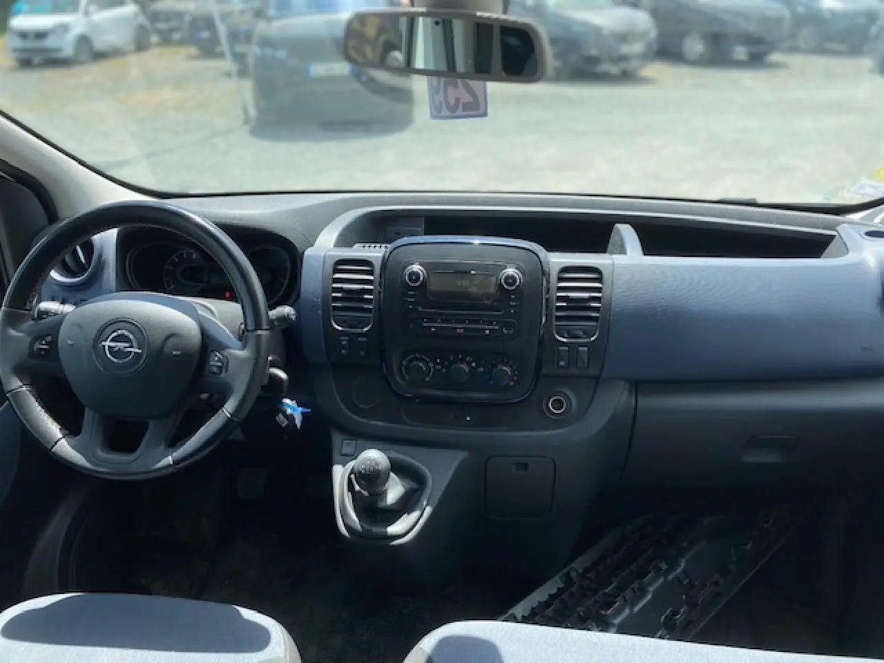 Vue intérieure du tableau de bord et volant d'un Opel Vivaro blanc 2018 avec boîte manuelle et commandes intégrées.