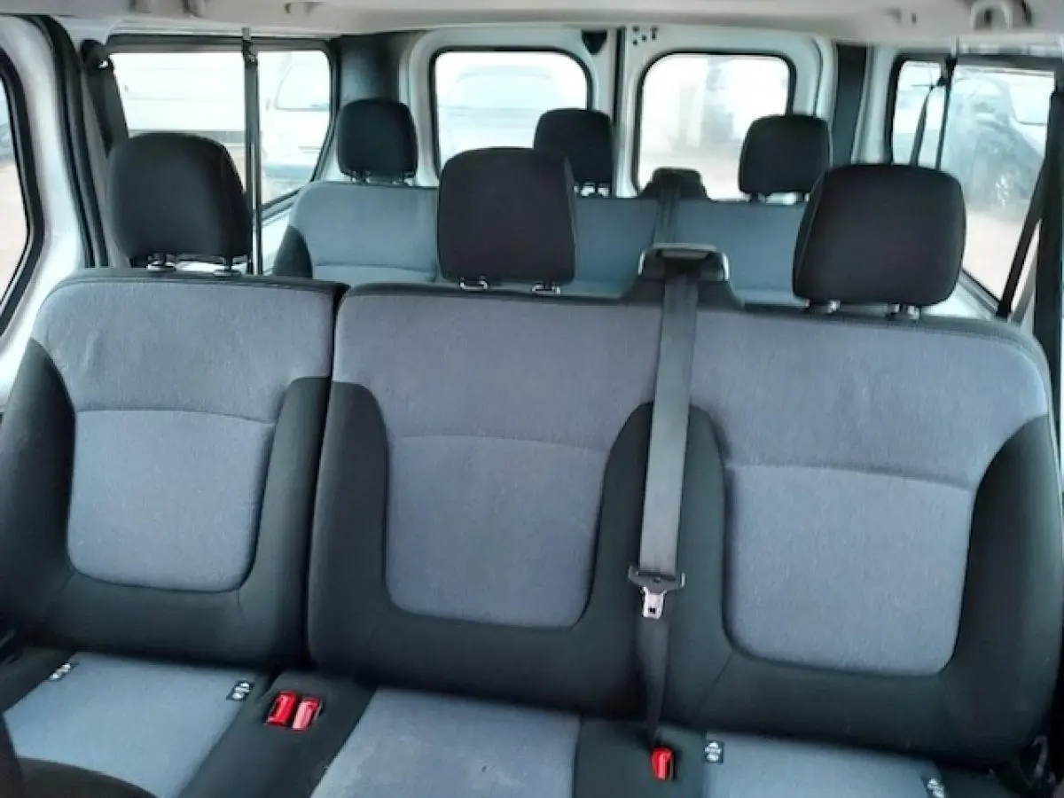 Vue intérieure des banquettes arrière grises et noires d'un Opel Vivaro blanc 9 places, montrant les appuie-têtes et ceinture de sécurité.
